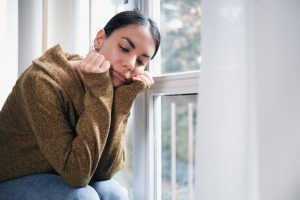 Homesick person leaning window.